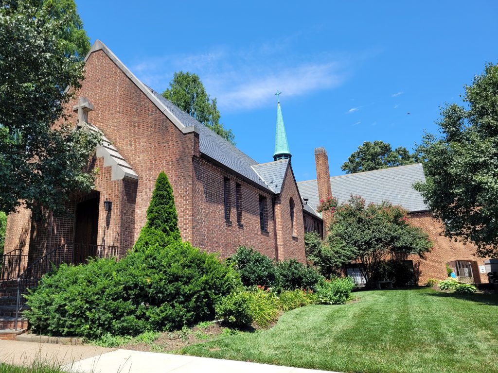 A brick church building with steeple on a sunny day