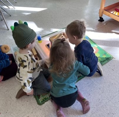 Three children kneel facing each other