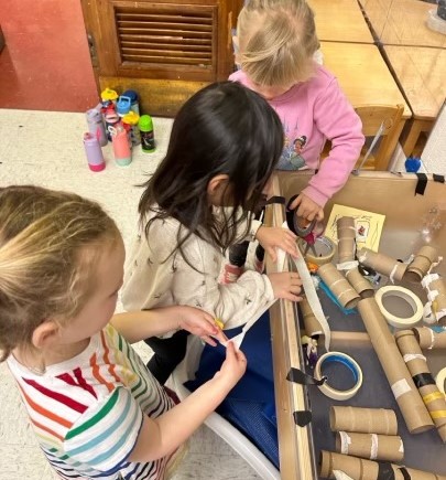 Children sit at a table with art supplies