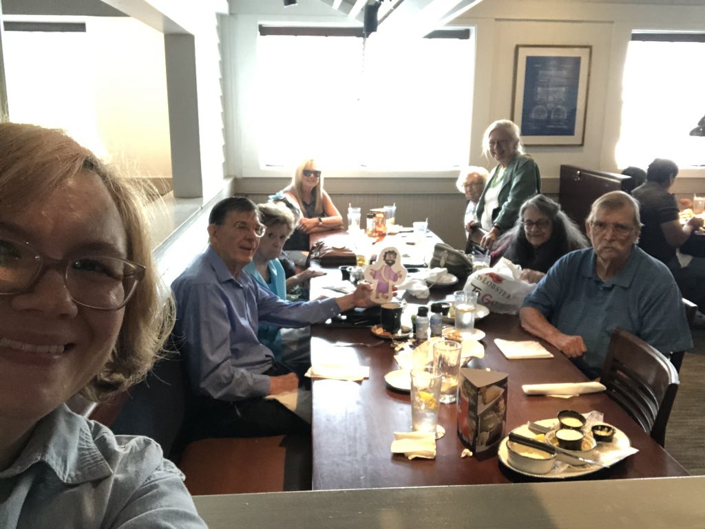A groups of adults sit at a table for a meal together