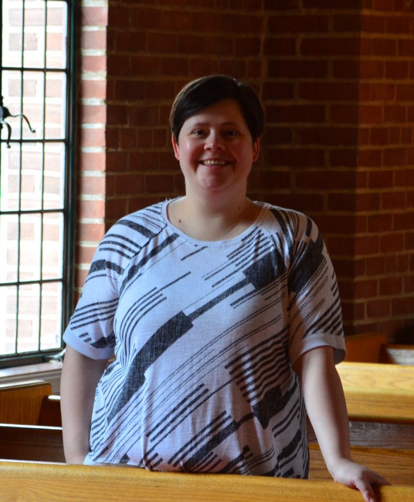 A woman in a black and white shirt standing in front of a window