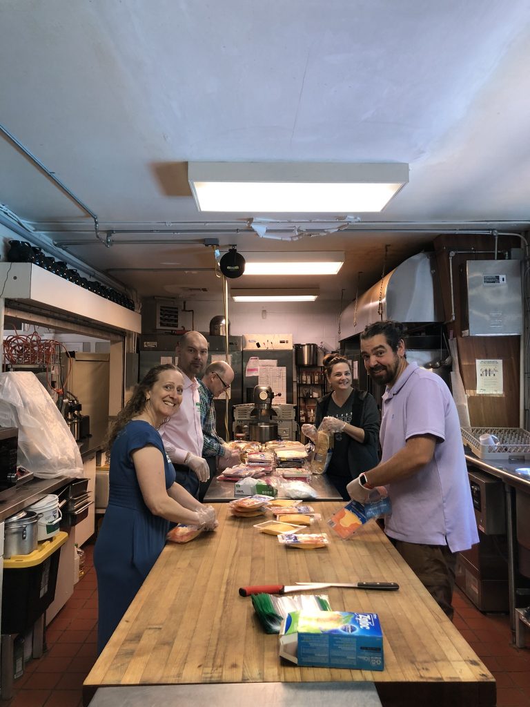 A group of people stand around a table preparing food