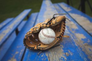 Close up of a baseball mitt holding a ball lying on a blue bench