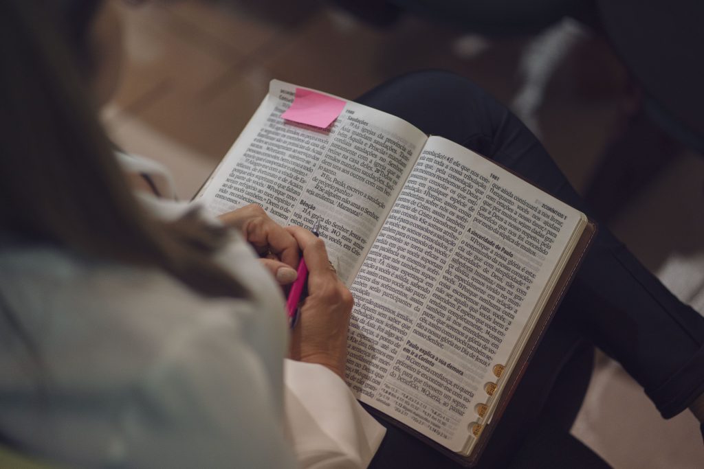 Close up of a bible in a person's lap, with their hands folder on the page