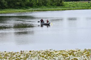 Silhouette of two people canoeing in the distance on a flat lake
