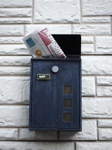 A newspaper protruding from the top of a mailbox