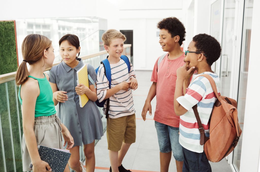 A group of teens with backpacks chatting in a hallway